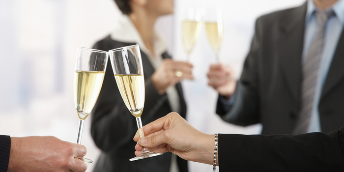 A group of businesspeople clink champagne glasses together