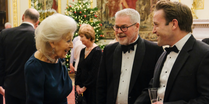 Princess Alexandra greets two men in tuxedos at a Christmas black-tie event
