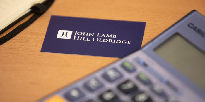 A John Lamb Hill Oldridge business card is placed on a table