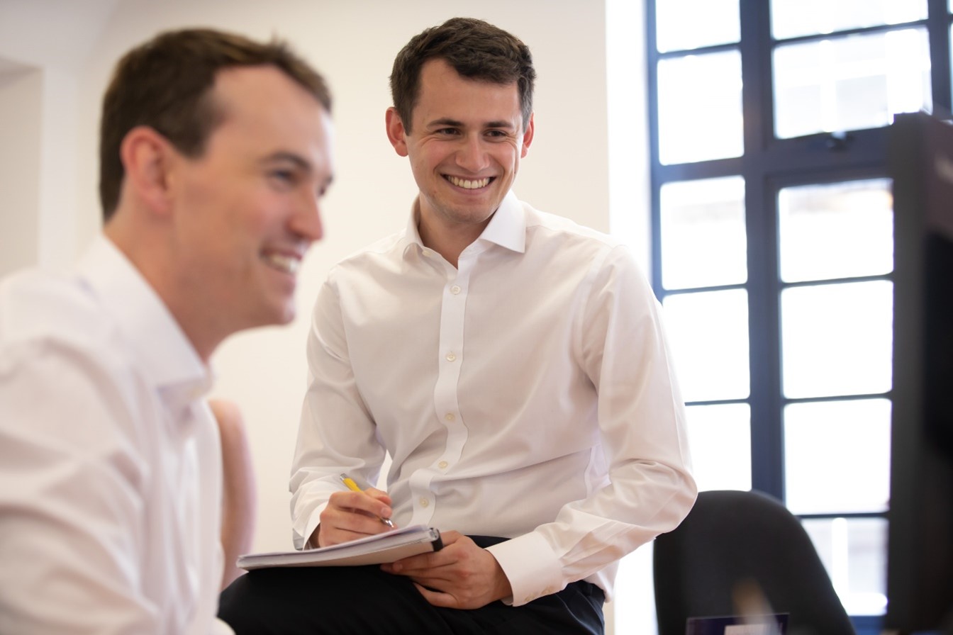 Two team members look at a computer screen smiling.